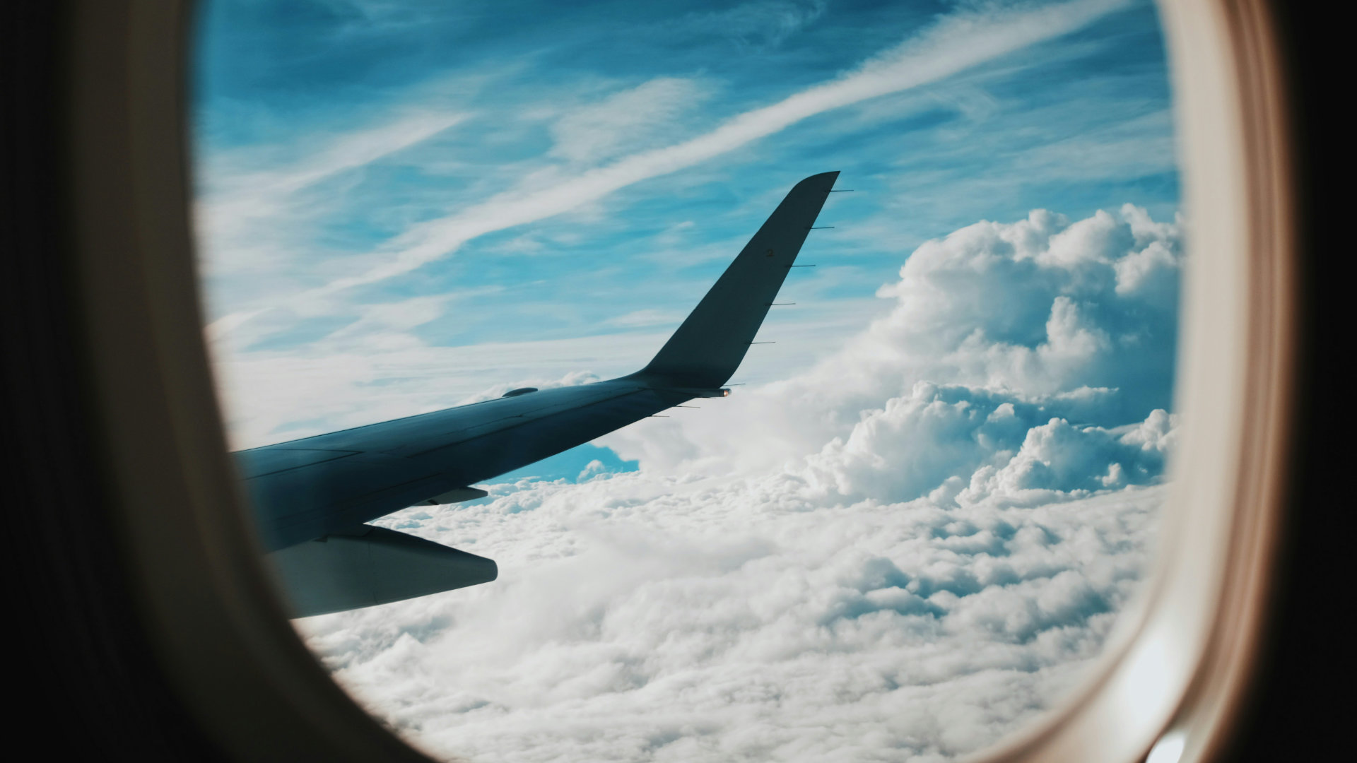 A view through an airplane window of a sunlit sky above the clouds, symbolizing freedom from fear