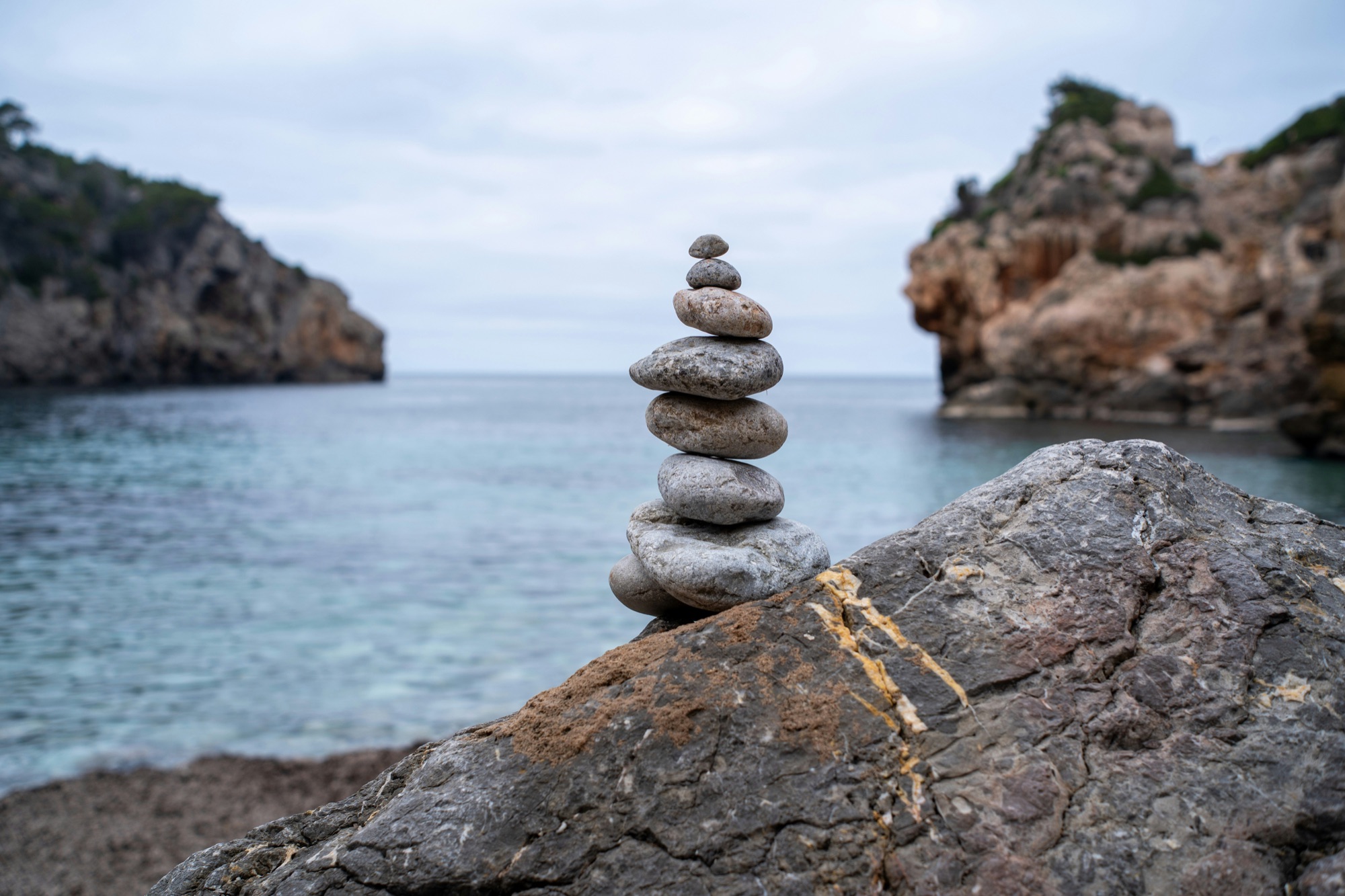 A stack of balanced stones resting on a calm rocky shore